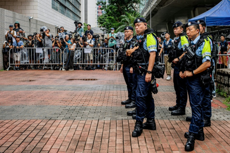 Des policiers se tiennent près de l'espace réservé aux médias devant les tribunaux de première instance de West Kowloon, avant le verdict du procès pour atteinte à la sécurité nationale de deux militants prodémocratie de la mémoire de Tiananmen, à Hong Kong, le 21 août 2026 ( AFP / Leung Man Hei )