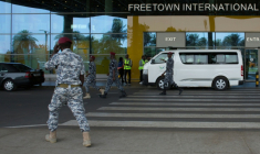 Des agents de sécurité escortent des migrants vers un centre de l'Agence nationale de santé publique (NPHA) après leur arrivée à l'aéroport international de Freetown, le 20 mai 2026 à Lungi, en Sierra Leone ( AFP / - )