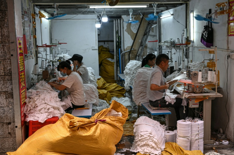 Des ouvriers confectionnant des vêtements dans un petit atelier de Canton, dans le sud de la Chine, le 16 avril 2026 ( AFP / Jade GAO )