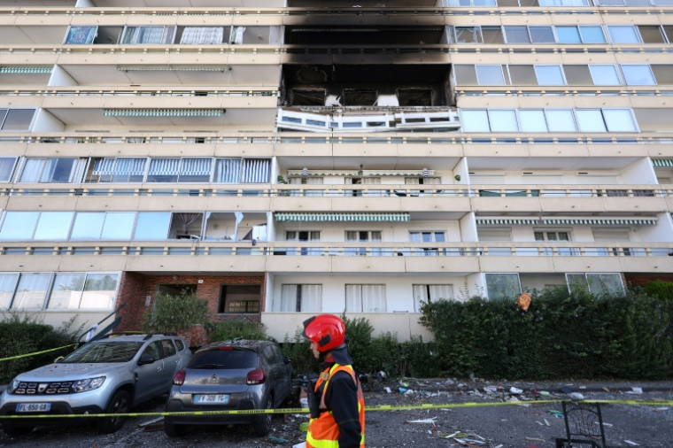 Un pompier passe devant la façade calcinée d'un immeuble suite de l'explosion d'une bouteille de gaz, dans le quartier des Minguettes à Vénissieux, dans la banlieue sud de la ville de Lyon, le 18 août 2025 ( AFP / Alex MARTIN )