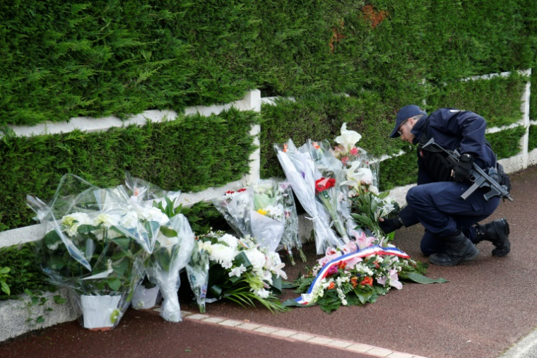 Un policier dépose des fleurs à Magnanville, le 15 juin 2016 après l'assasinat d'un couple de policiers ( AFP / MATTHIEU ALEXANDRE )