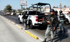 Des membres de la Garde nationale près d'un bus incendié par des groupes criminels en représailles à une opération menée à Jalisco, dans l'État de Jalisco, au Mexique, le 22 février 2026. ( AFP / Ulises RUIZ )