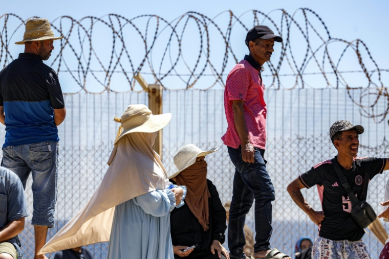 Des personnes attendent derrière une clôture surmontée de barbelés le retour de proches ayant tenté de franchir la frontière pour entrer dans l’enclave espagnole de Ceuta, le 2 août 2026 à Fnideq ( AFP / Abdel Majid BZIOUAT )