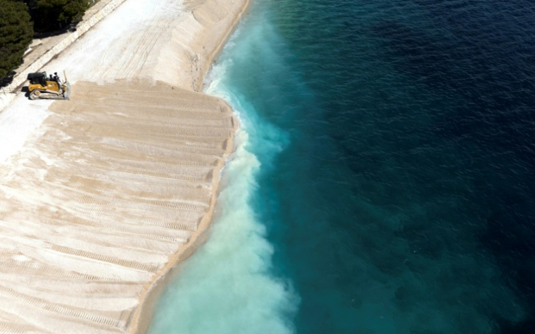 Vue aérienne d'un engin de chantier draguant du sable pour agrandir une plage artificielle à Primosten, le 9 mai 2025 en Croatie ( AFP / ELVIS BARUKCIC )