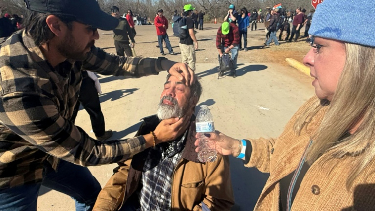 Des manifestants aident un homme touché par des gaz lacrymogènes lancés par les forces de l'ordre lors d'une manifestation à Dilley, Etats-Unis, le 28 janvier 2026 ( AFP / Moisés ÁVILA )