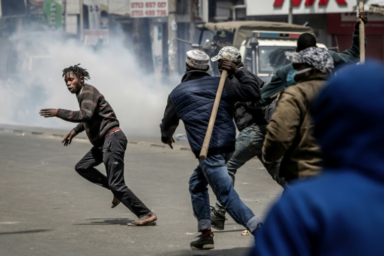 Des hommes armés de bâtons et de gourdins poursuivent un manifestant, lors d'affrontements à Nairobi, le 17 juin 2025 au Kenya ( AFP / Luis TATO )