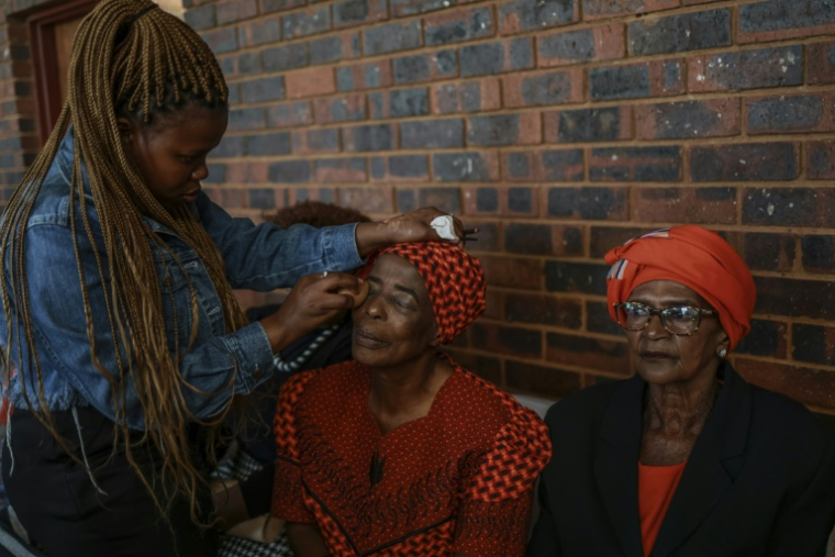 Nozizwe Khumalo, 77 ans, au centre, se fait maquiller avant le concours de beauté réservé aux grands-mères à Thokoza, en Afrique du Sud, le 13 mai 2025 ( AFP / Phill Magakoe )