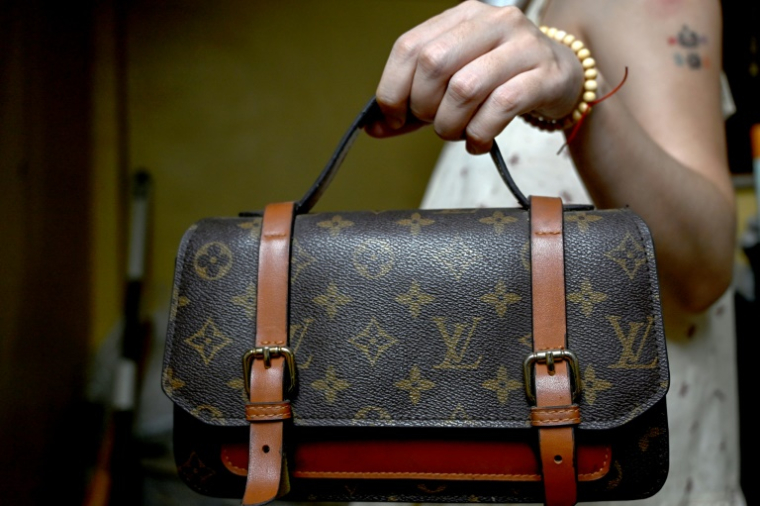 Une femme tient un sac à main Louis Vuitton contrefait, chez elle à Hanoï, le 10 juin 2025 au Vietnam ( AFP / Nhac NGUYEN )