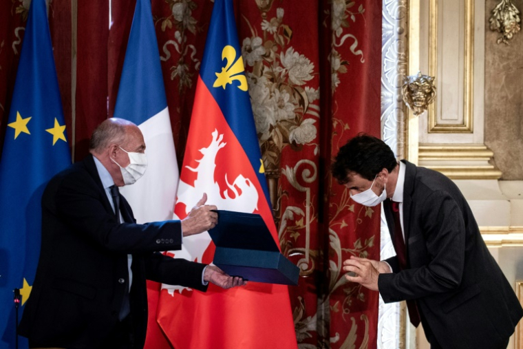 L'écologiste Grégory Doucet (d) reçoit l'écharpe de maire des mains du maire sortant et ancien ministre de l'Intérieur Gérard Collomb (g), le 4 juillet 2020 ( AFP / JEFF PACHOUD )