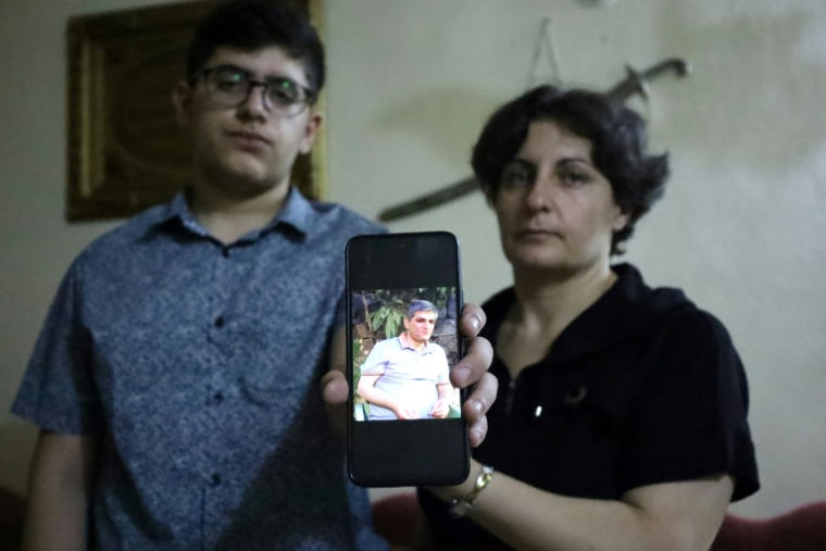 Amjad Zarifah, la veuve du Franco-syrien Firas Abou Lteif, tué la semaine dernière avec son beau-frère dans la ville à majorité druze de Soueida, et son fils Rami qui tient une photo de son père à leur domicile, le 23 juillet 2025 à Soueida ( AFP / SHADI AL DUBAISI )