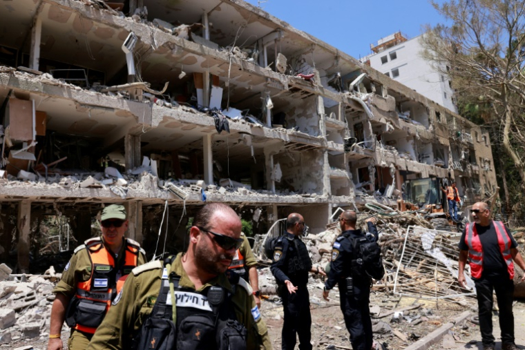Les forces de sécurité israéliennes et les premiers secours sont rassemblés devant un bâtiment gravement endommagé par une frappe iranienne à Tel-Aviv, le 22 juin 2025 ( AFP / Menahem Kahana )