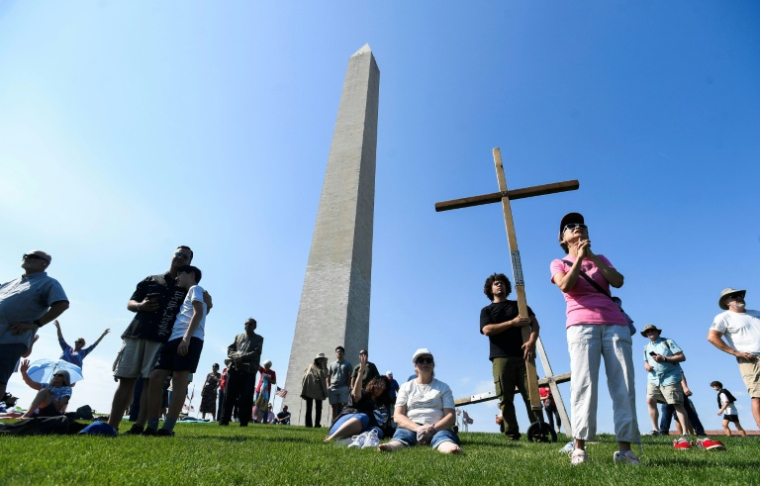 Des fidèles chrétiens prient devant le Washington Monument à la veille d'une journée de "prière nationale" à Washington le 16 mai 2026. ( AFP / Matthew Hatcher )