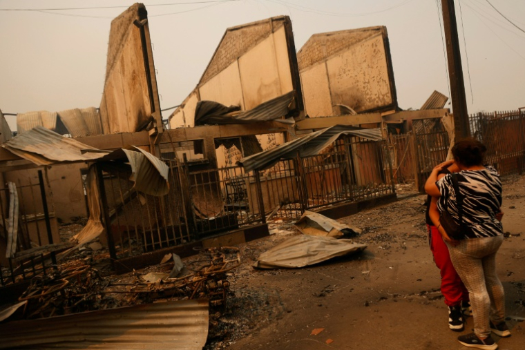 Des habitants éplorés devant des maisons détruites après un incendie de forêt à Concepción, au Chili, le 18 janvier 2026 ( AFP / Raul BRAVO )