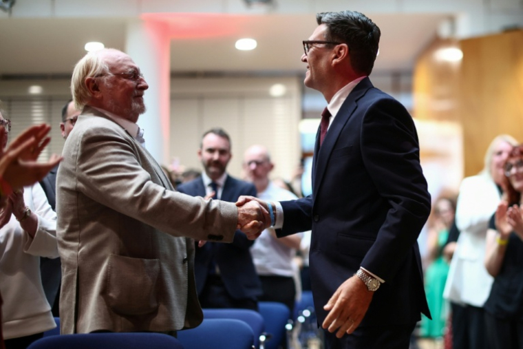 Andy Burnham (à droite) serre la main de Neil Kinnock (à gauche), ancien chef du Parti travailliste dans les années 1980 et 1990, à son arrivée, avant d'être confirmé comme nouveau chef du Parti travailliste et prochain Premier ministre du pays, lors du "congrès extraordinaire du Parti travailliste" qui s'est tenu dans le centre de Londres le 17 juillet 2026 ( POOL / Henry Nicholls )