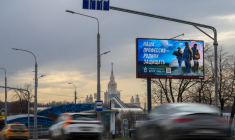 Des voitures passent devant un panneau promouvant le service militaire dans les stands de l'armée russe à Moscou