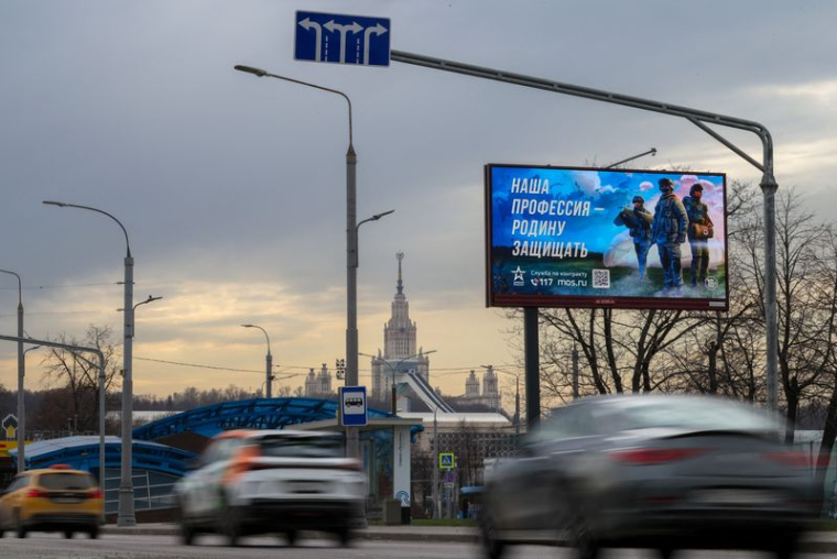Des voitures passent devant un panneau promouvant le service militaire dans les stands de l'armée russe à Moscou
