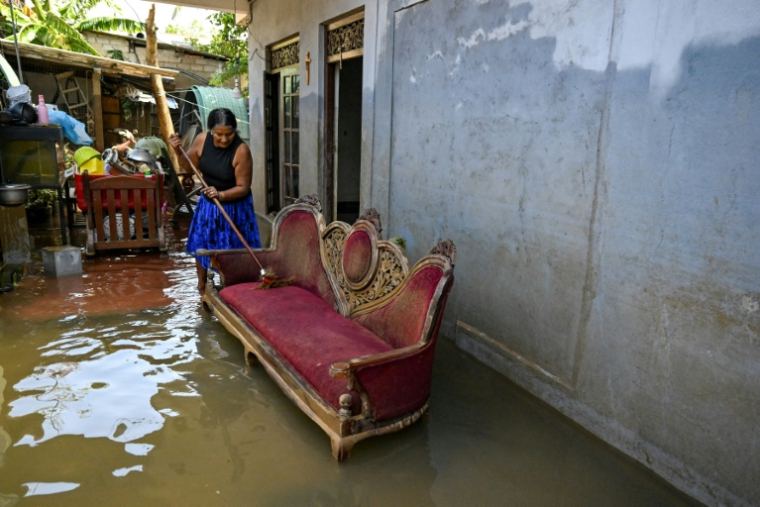 Une femme récupère ses affaires dans une maison inondée, à Wellampitiya, en périphérie de Colombo, au Sri Lanka, le 3 décembre 2025 ( AFP / Ishara S. KODIKARA )