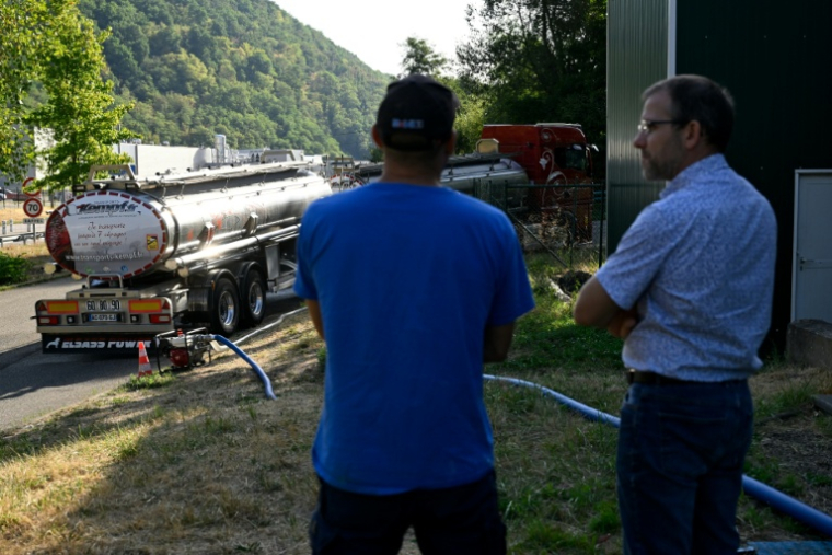 Xavier Barbin, directeur adjoint du Syndicat des eaux et de l'assainissement (SDEA) Centre-Alsace, à droite, discute avec un employé du SDEA pendant qu'un camion-citerne ravitaille en eau la commune de Sainte-Marie-aux-Mines, dans le Haut-Rhin, le 11 août 2026 ( AFP / Jean-Christophe VERHAEGEN )