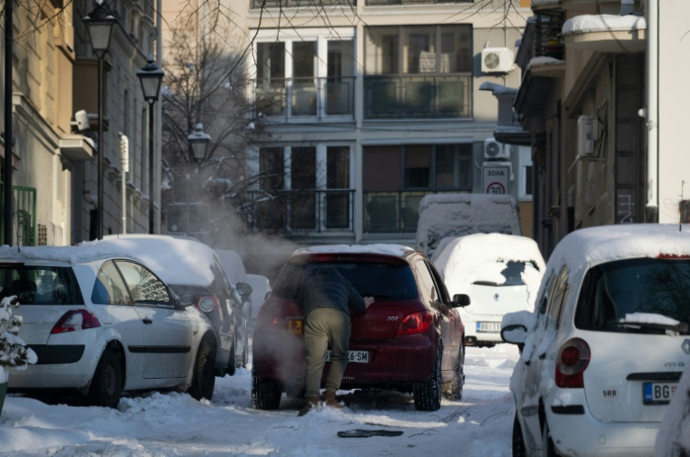 Un homme pousse une voiture immobilisée dans une rue enneigée de Belgrade, le 8 janvier 2026 ( AFP / OLIVER BUNIC )
