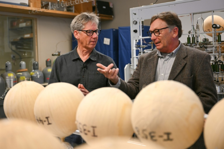 Les scientifiques Ralph Keeling et Tim Lueker discutent devant des bonbonnes contenant de l'air, analysées par des machines pour déterminer leur concentration en CO2, le 11 avril 2025 à San Diego, en Californie ( AFP / Patrick T. Fallon )