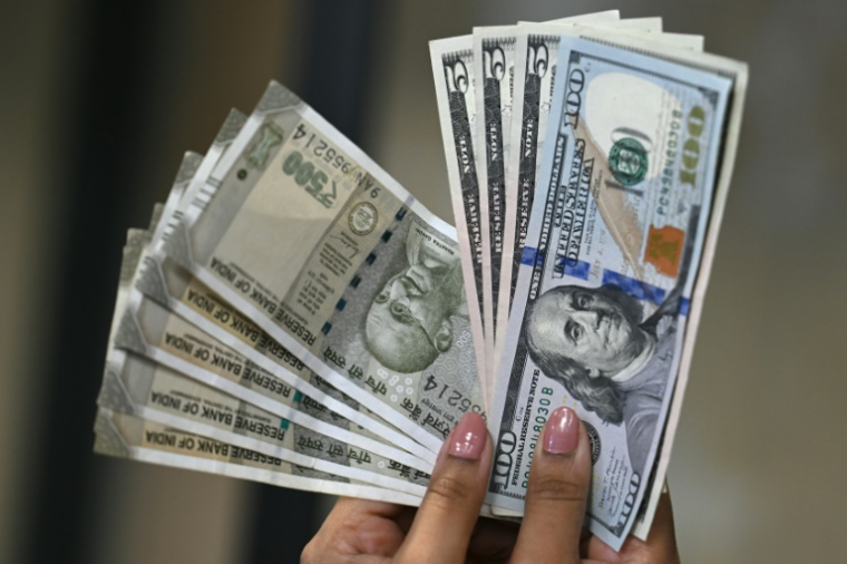 Des billets de banque en roupies indiennes (g) et en dollars américains dans un bureau de change à New Delhi, le 26 août 2025 en Inde ( AFP / Arun SANKAR )