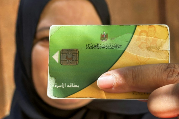 Une femme tient sa carte d'aide alimentaire, utilisée pour acheter des denrées alimentaires, au Caire, le 17 août 2026 ( AFP / Khaled DESOUKI )