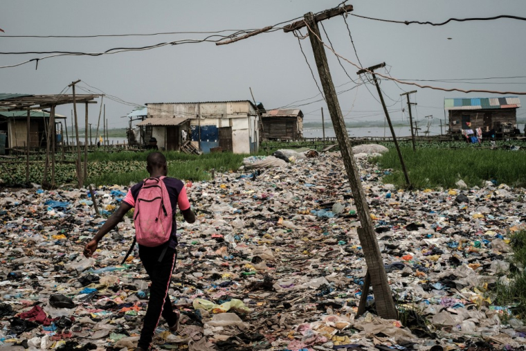 Un homme marche sur des déchets plastiques, dans la région de Mosafejo à Lagos (Nigeria) le 12 février 2019. Photo d'illustration. ( AFP / YASUYOSHI CHIBA )