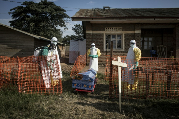 Des personnels médicaux désinfectent le cercueil d'un patient décédé à l'intérieur d'un centre de traitement d'Ebola géré par l'Alliance pour l'action médicale internationale (Alima), le 13 août 2018 à Beni, en RDC ( AFP / John WESSELS )