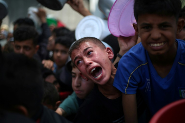 Des enfants palestiniens attendent de recevoir de la nourriture à un point de distribution à Nousseirat, dans le centre de la bande de Gaza, le 11 juin 2025 ( AFP / Eyad BABA )