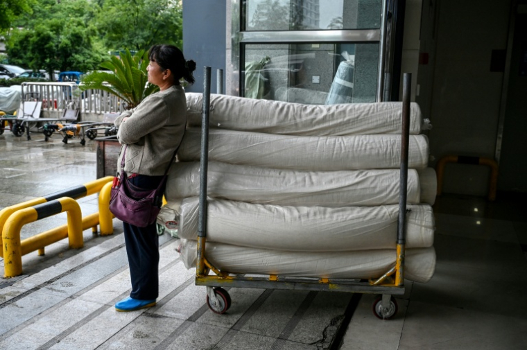 Une femme se tient à côté de rouleaux de tissu dans le district de Keqiao à Shaoxing, dans la province chinoise du Zhejiang, le 8 mai 2025 ( AFP / Greg Baker )