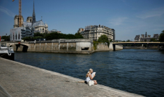 Une femme, assise sur les quais de la Seine, se rafraîchit avec un éventail lors d'une vague de chaleur précoce, le 28 mai 2026 à Paris ( AFP / SIMON WOHLFAHRT )
