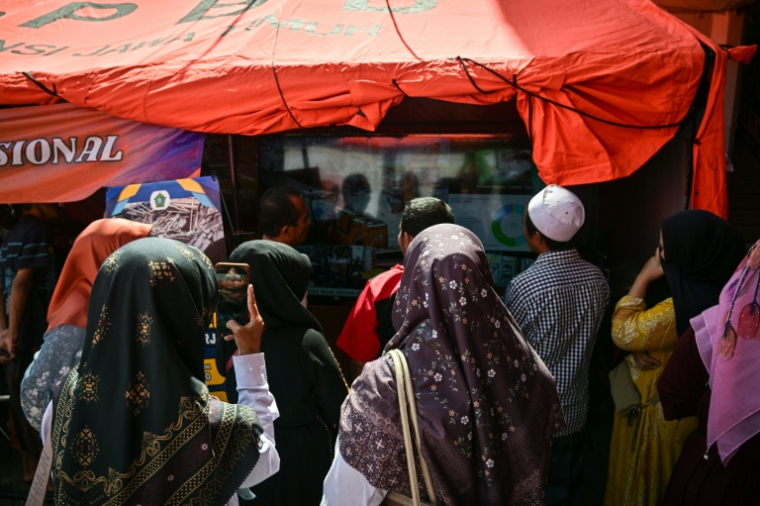 Des proches des élèves disparus regardent une retransmission en direct de l'opération de sauvetage près de l'internat islamique effondré d'Al Khoziny, à Sidoarjo, dans l'est de Java, le 6 octobre 2025 en Indonésie ( AFP / JUNI KRISWANTO )