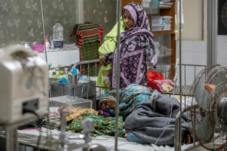 Une femme dort près d'un enfant atteint de la rougeole à l'hôpital Shishu à Dacca le 6 mai 2026 ( AFP / Salahuddin AHMED )