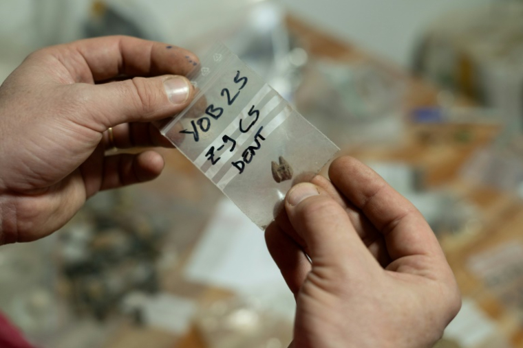 Un archéologue tient un sac contenant une dent trouvée dans la grotte de Youmbidi (Gabon), dans un laboratoire de Libreville le 23 juin 2025 ( AFP / Léa NKAMLEUN FOSSO )