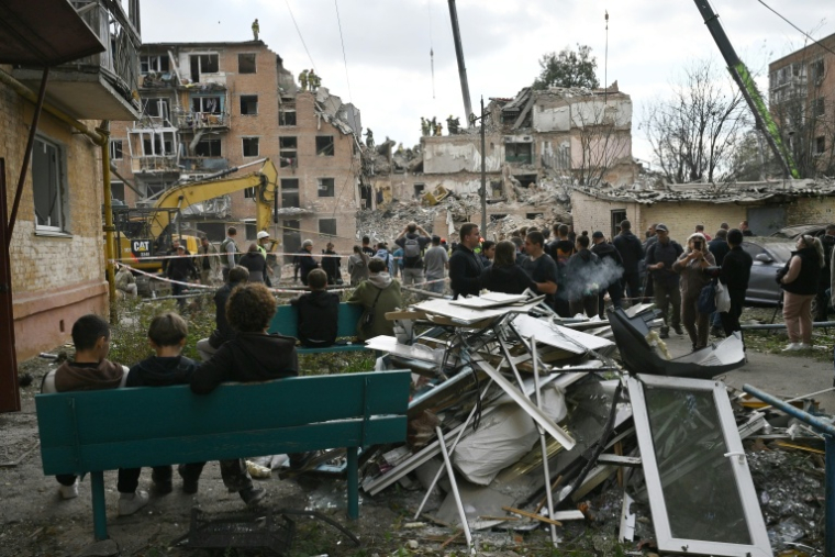 Des habitants observent des secouristes travailler dans les décombres d'un immeuble détruit par une frappe russe à Pryluky, en Ukraine, le 7 octobre 2026 ( AFP / Genya Savilov )