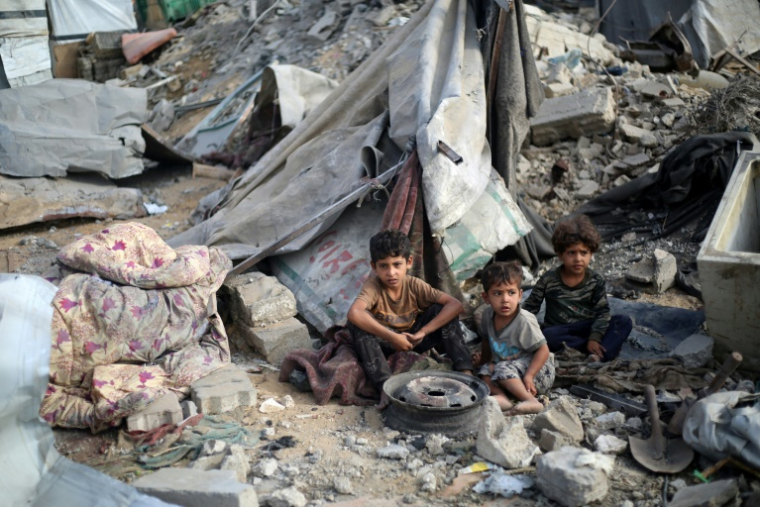 Des enfants palestiniens sont assis au milieu des destructions après une frappe israélienne sur le camp de réfugiés de Bureij, dans le centre de la bande de Gaza, le 10 juillet 2025 ( AFP / Eyad BABA )
