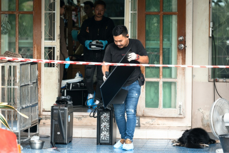 Un enquêteur emporte un ordinateur hors de la maison où un adolescent a tué ses grands-parents avant de perpétrer une fusillade dans une école au nord de Bangkok, la capitale de la Thaïlande (7 août 2026) ( AFP / Chanakarn LAOSARAKHAM )