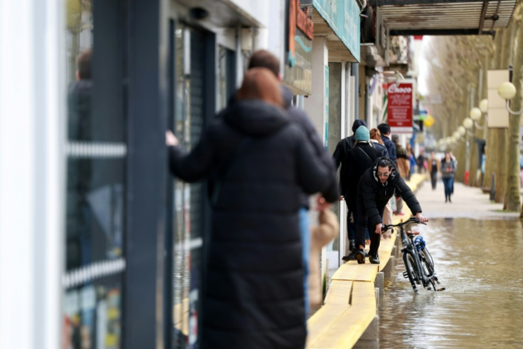 Un habitant pousse son vélo dans une rue inondée par les crues, le 21 février 2026 à Saintes, en Charente-Maritime ( AFP / ROMAIN PERROCHEAU )