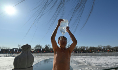 Un amateur de bain en eau froide s'asperge sur les rives lac Shichahai, au coeur de Pékin, le 20 juin 2026 ( AFP / Adek BERRY )