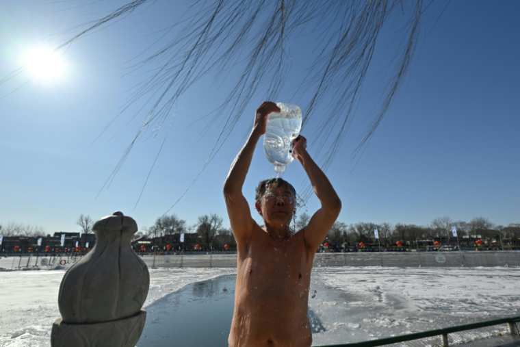 Un amateur de bain en eau froide s'asperge sur les rives lac Shichahai, au coeur de Pékin, le 20 juin 2026 ( AFP / Adek BERRY )