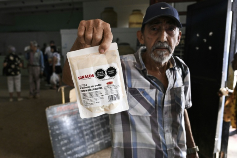 Un homme montre un paquet de viande de poulet sous vide, faisant partie de l’aide humanitaire offerte par le Mexique aux familles cubaines, dans un entrepôt de La Havane, le 6 mars 2026. ( AFP / YAMIL LAGE )