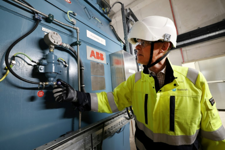 Guy Nicholson, responsable des solutions réseau neutres en carbone chez Statkraft, se tient près d'un volant d'inertie, le 7 août 2025 à Liverpool ( AFP / Darren Staples )
