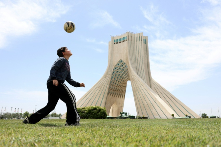 Un garçon iranien joue au football près de la tour Azadi à Téhéran le 7 mai 2026.  ( AFP / - )
