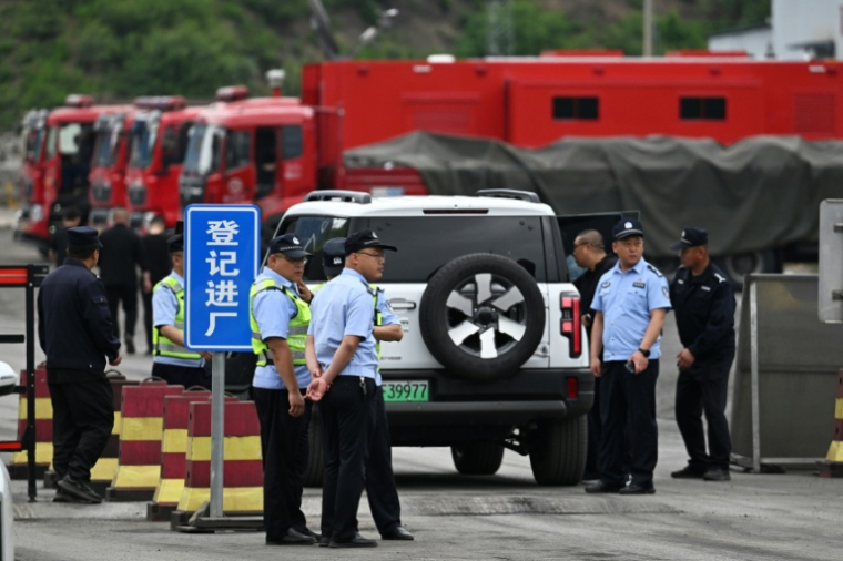 Des policiers devant la route menant à la mine de charbon de Liushenyu, où un coup de grisou dévastateur a fait au moins 82 morts, le 24 mai 2026 dans le district administratif de Qinyuan, dans la province chinoise septentrionale du Shanxi ( AFP / GREG BAKER )