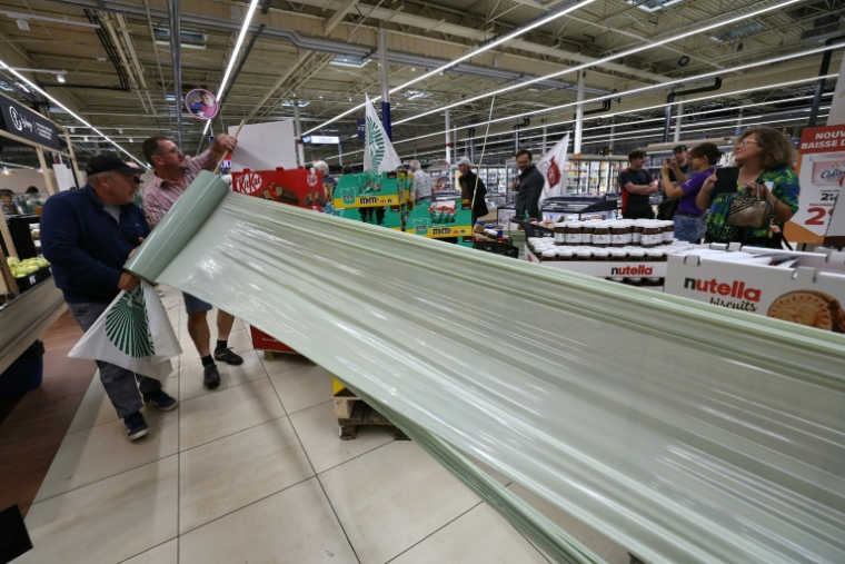 Des membres des syndicats agricoles FDSEA 72 et Jeunes Agriculteurs (JA) enveloppent des produits des produits contenant de l'acétamipride, un pesticide néonicotinoïde, retirés des rayons lors d'une opération de protestation dans un supermarché de Mundolsheim, le 20 août 2025 dans le Bas-Rhin ( AFP / Frederick FLORIN )