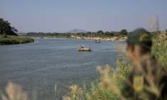 Un membre de la police aux frontières sud-africaine regarde un radeau traverser illégalement le fleuve Limpopo depuis le Zimbabwe, le 9 juillet 2026 ( AFP / EMMANUEL CROSET )