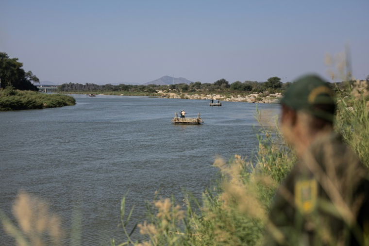 Un membre de la police aux frontières sud-africaine regarde un radeau traverser illégalement le fleuve Limpopo depuis le Zimbabwe, le 9 juillet 2026 ( AFP / EMMANUEL CROSET )