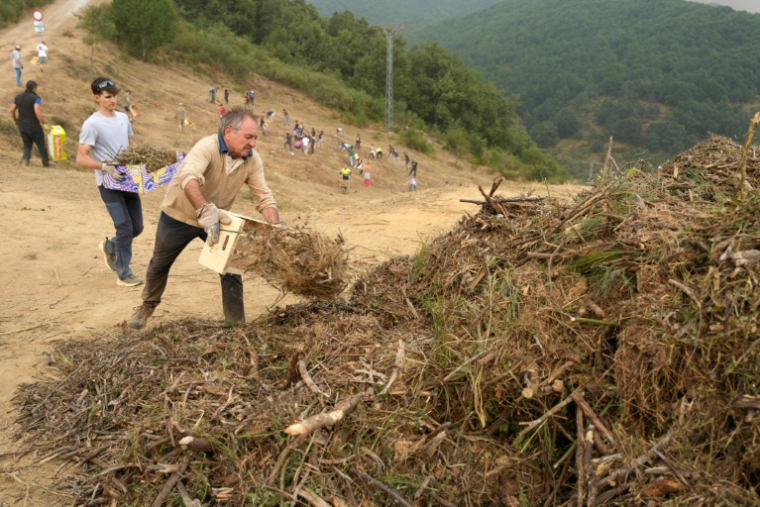 Des habitants réalisent des travaux de déboisement en prévision d'un possible arrivée du feu provenant de l'incendie du parc national des Picos de Europa, dans la ville de Riano, en Castille-et-León, en Espagne, le 18 août 2025 ( AFP / CESAR MANSO )