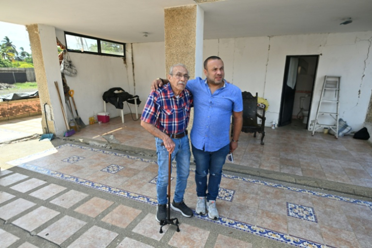 L'ingénieur Elias Chayeb (à g.) et son fils, l'ingénieur Elias Eduardo Chayeb, posent pour une photo à Catia La Mar, dans l'Etat de La Guaira (Venezuela), le 6 juillet 2026. Au milieu d'un pâté d'immeubles réduit à l'état de ruines, un modeste bâtiment de trois étages qu'ils ont contribué à construire est toujours debout. Elias Chayeb a fondu en larmes en constatant qu'il avait résisté au double séisme qui a fait plus de 3.500 morts au Venezuela. ( AFP / Juan BARRETO )