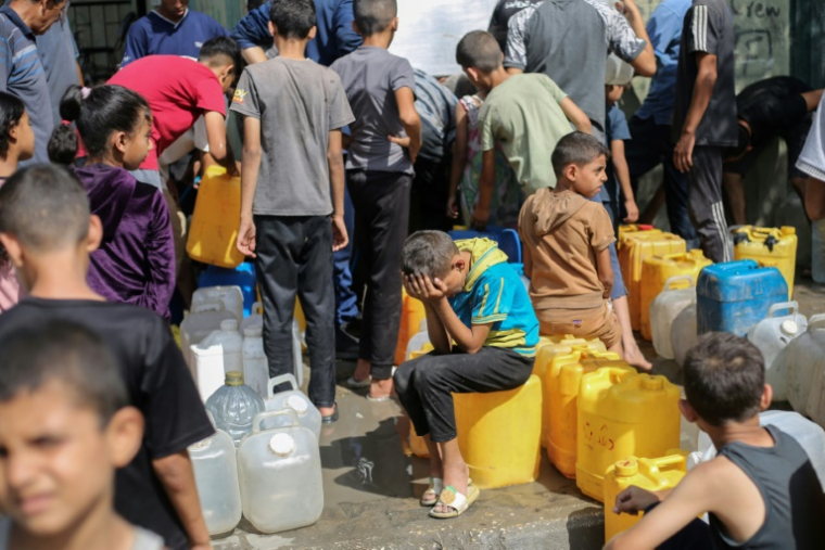 Des enfants palestiniens sont assis sur leurs conteneurs en attendant de les remplir à un point de distribution à Nousseirat, dans la bande de Gaza, le 4 septembre 2025 ( AFP / Eyad BABA )